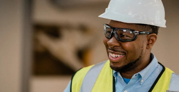 Smiling Rainbow Restoration technician wearing a safety vest and hard hat.